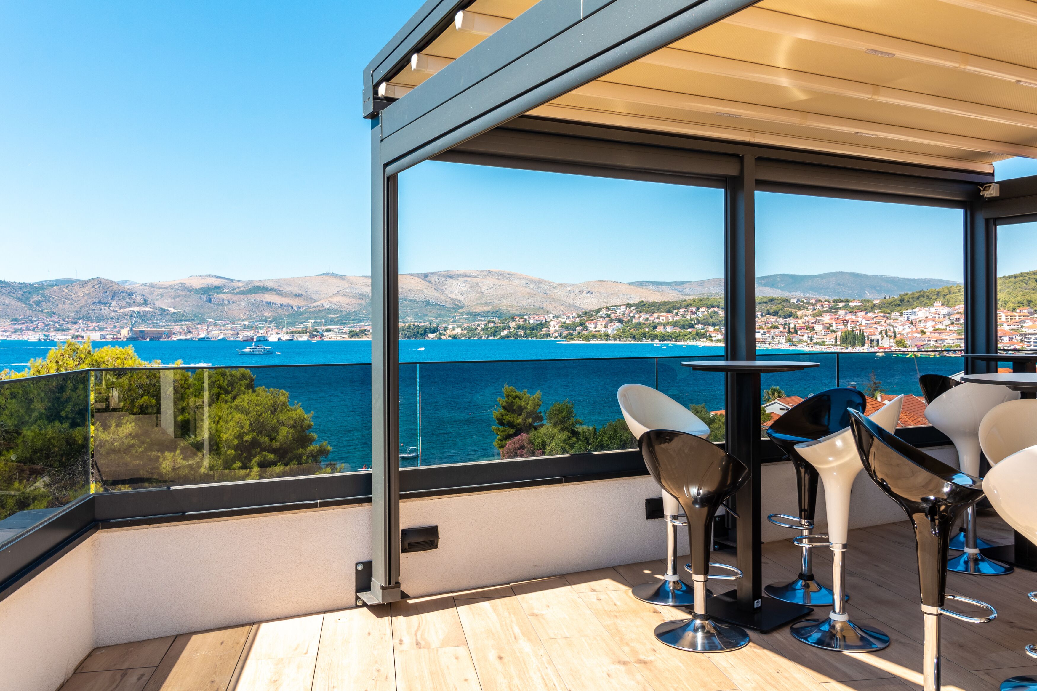 Un balcone con vista libera sul mare e una città in lontananza.
