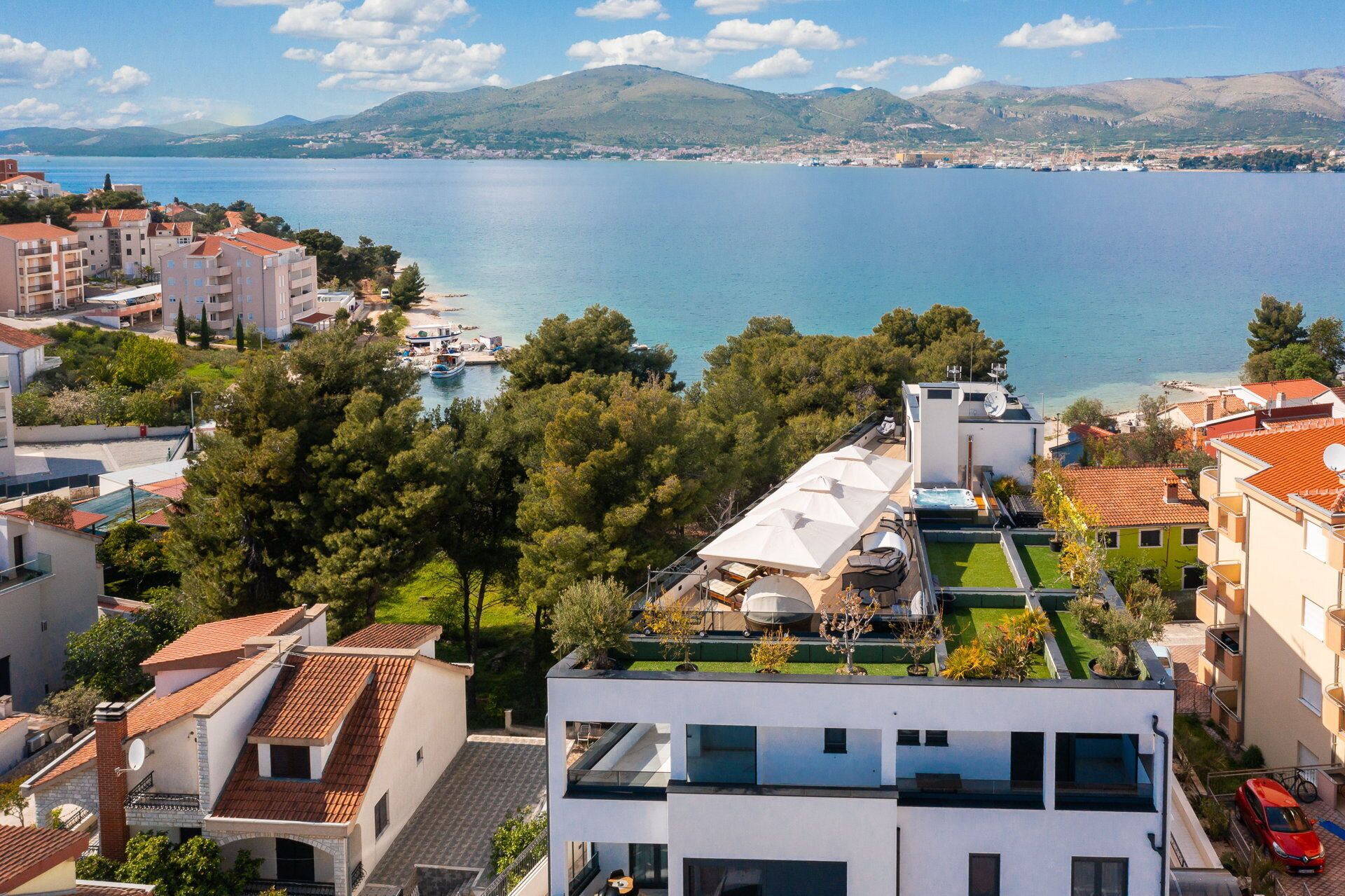 Un quartier résidentiel en bord de mer, avec des immeubles modernes, un port de plaisance et une vue sur la mer et les montagnes.