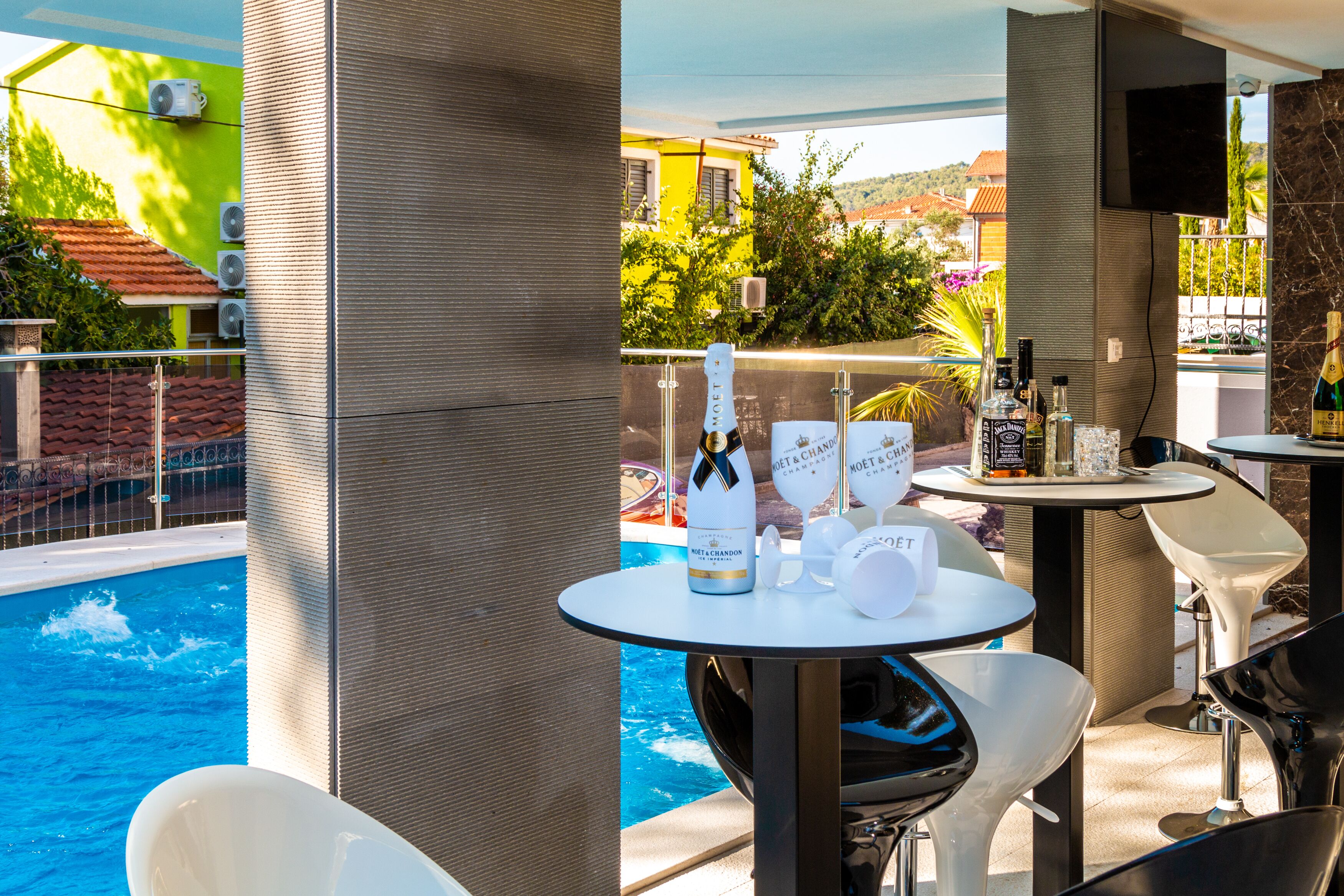 A poolside area with a table set for a drink, a bottle of champagne, and a bottle of water.
