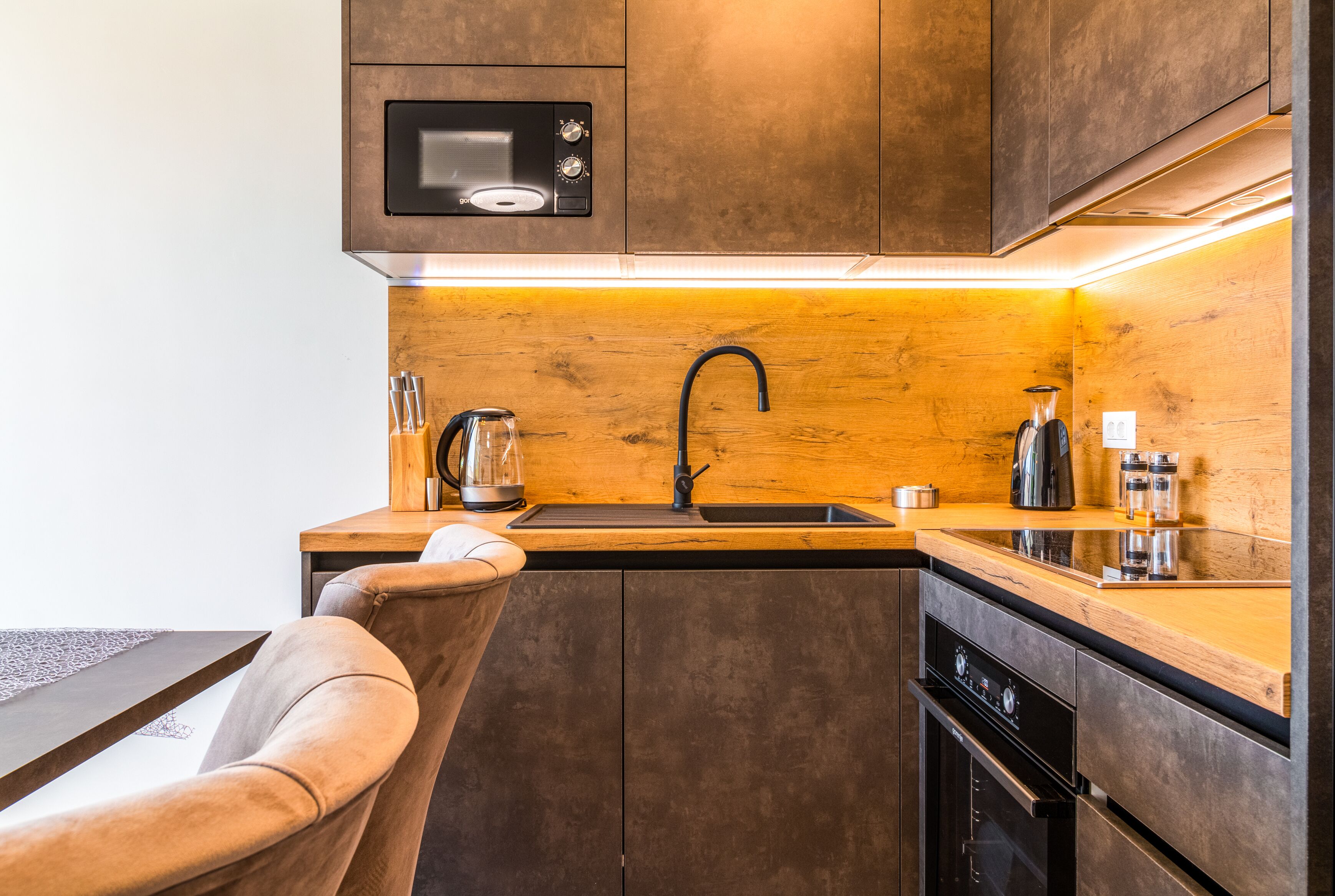 A modern kitchen with wooden cabinetry, a stainless steel sink, and a built-in oven.