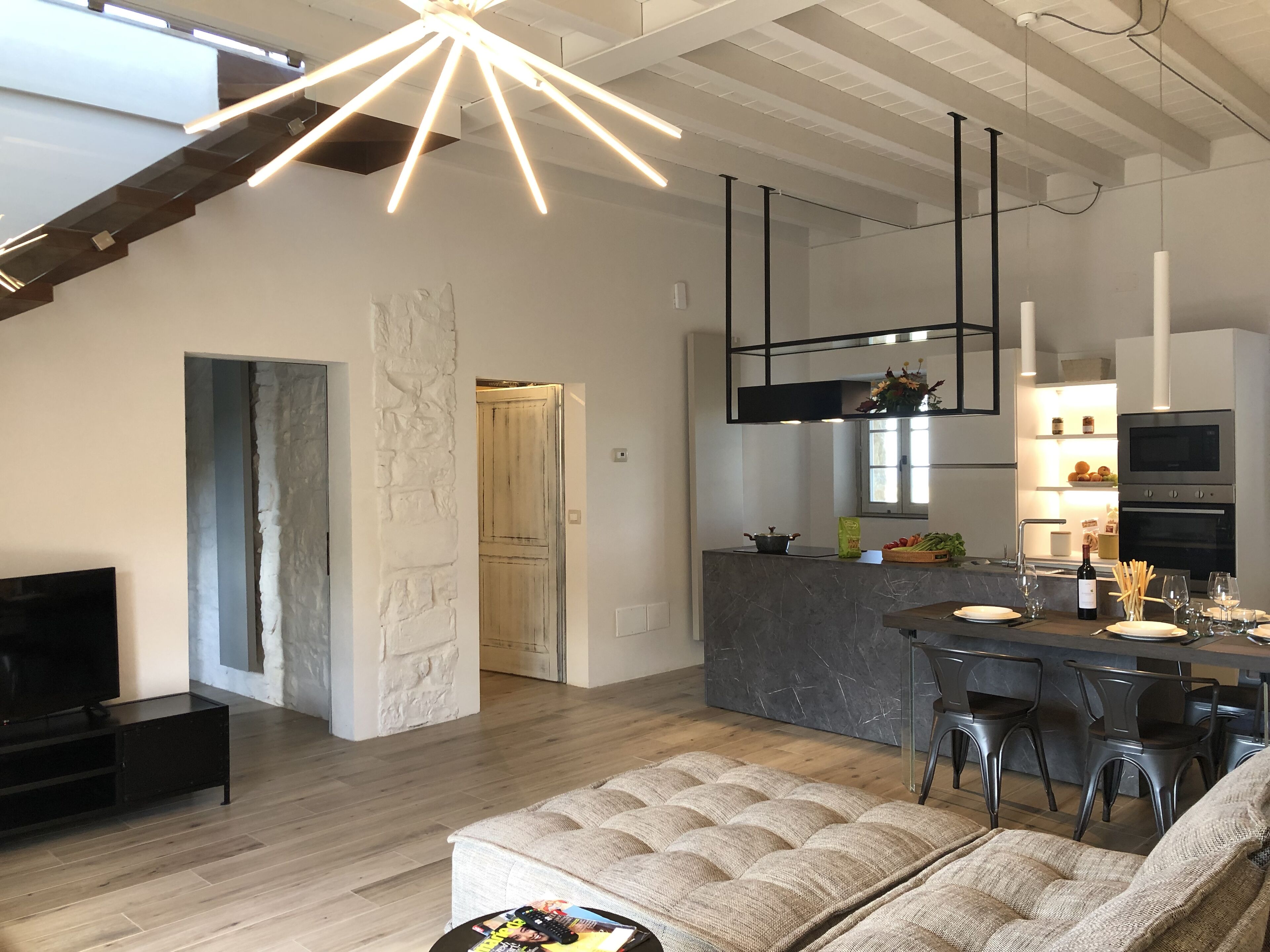 Een moderne keuken met een centraal eiland, een zithoek met een bank en stoelen, en een televisie in een hoek.