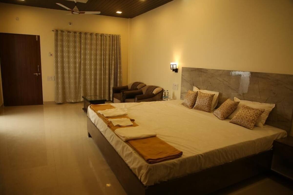 Une chambre d’hôtel avec un grand lit, un fauteuil massant, un ventilateur de plafond et une porte.