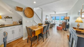 A spacious kitchen with a dining area, wooden flooring, and a view of the ocean. - Very Merry - Renovated Gulf-Front Escape, Steps To Beach (Panama City Beach)