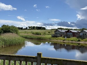 A lakeside view with wooden deck and cabins. - The Lake House -  a meadow lodge that sleeps 4 guests  in 2 bedrooms (Filey)