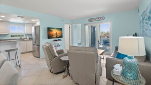 A modern kitchen with a refrigerator, a dining area with a table and chairs, and a view of the outside. - 🌴 Caprice Resort Unit #201 – Corner Gulf Front Condo with Water Views (Saint Pete Beach)
