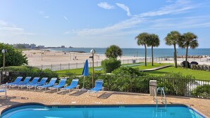 A pool area with lounge chairs, a view of the beach, and palm trees. - 🌴 Caprice Resort Unit #201 – Corner Gulf Front Condo with Water Views (Saint Pete Beach)
