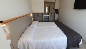 A hotel room with two beds, a desk with a mirror, a TV, and a small closet. - Estudio Vista Mar Muxia (Muxía)