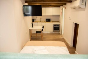 A compact bedroom with a bed, a small bedside table, and a TV mounted on the wall.