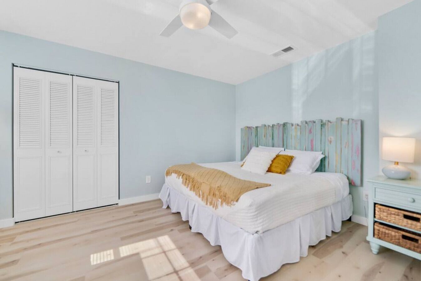 A bedroom with a bed, a ceiling fan, a nightstand, and a wardrobe.