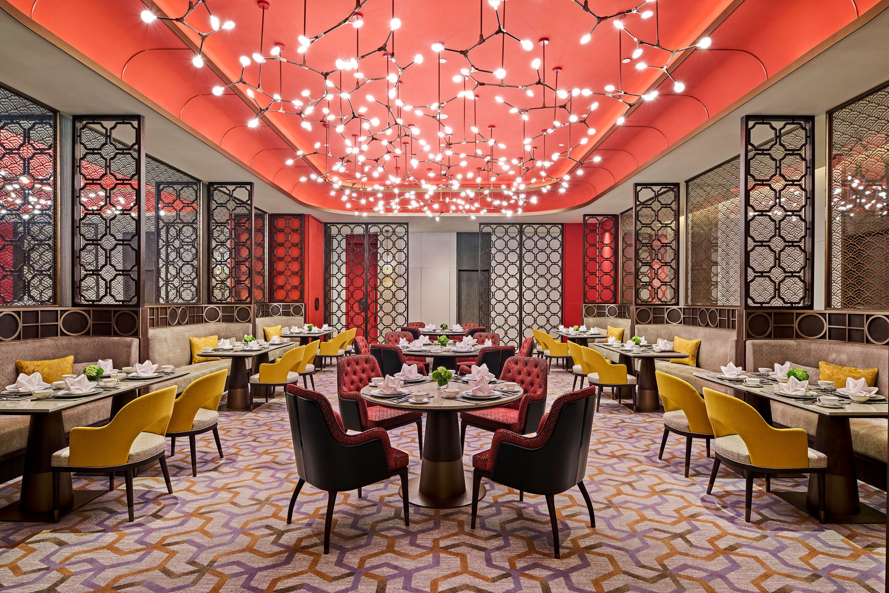 A restaurant with round tables, yellow chairs, and a patterned floor.