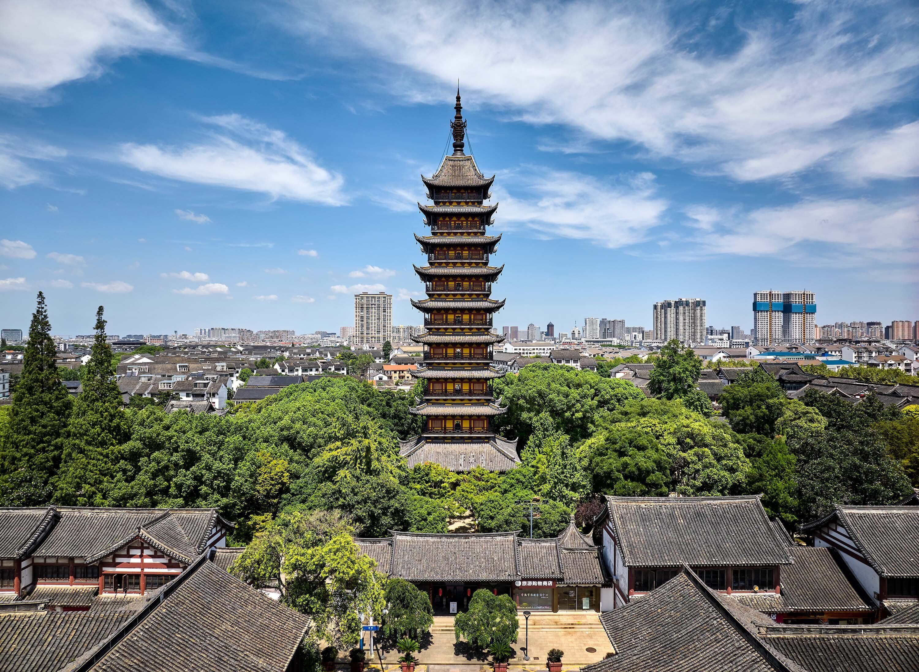 A traditional pagoda with multiple tiers, surrounded by lush greenery and traditional buildings.