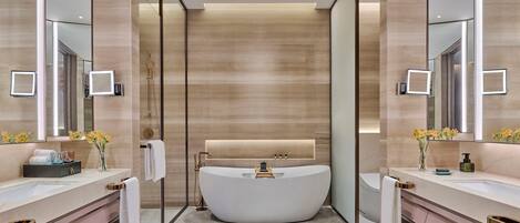 A modern bathroom with a freestanding bathtub, dual sinks, and a large mirror.