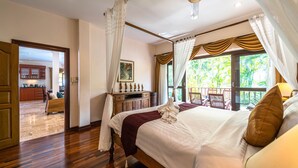 Ein geräumiges Schlafzimmer mit einem großen Bett, einem Deckenventilator und Blick ins Freie.