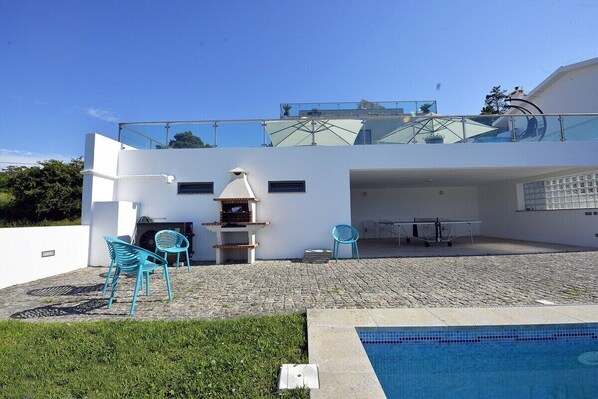 A modern house with a pool, outdoor seating, and a glass balustrade.