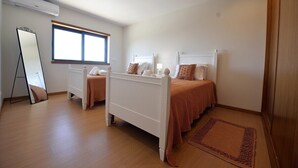 Une chambre avec deux lits simples, un grand miroir et une fenêtre.