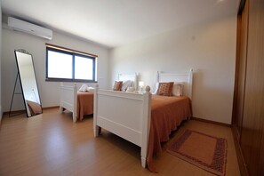 Ein Schlafzimmer mit zwei Einzelbetten, einem großen Spiegel und einem Fenster.