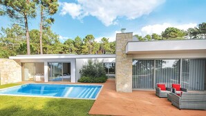 Een modern huis met een zwembad, terras en een stenen muur.