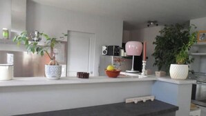 Una cocina moderna con una isla central, armarios blancos y un comedor con un taburete de bar.