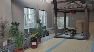 A covered outdoor area with potted plants, a pergola, and a seating area with tables and chairs.