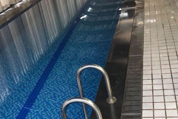 A swimming pool with a tiled floor and a metal ladder.