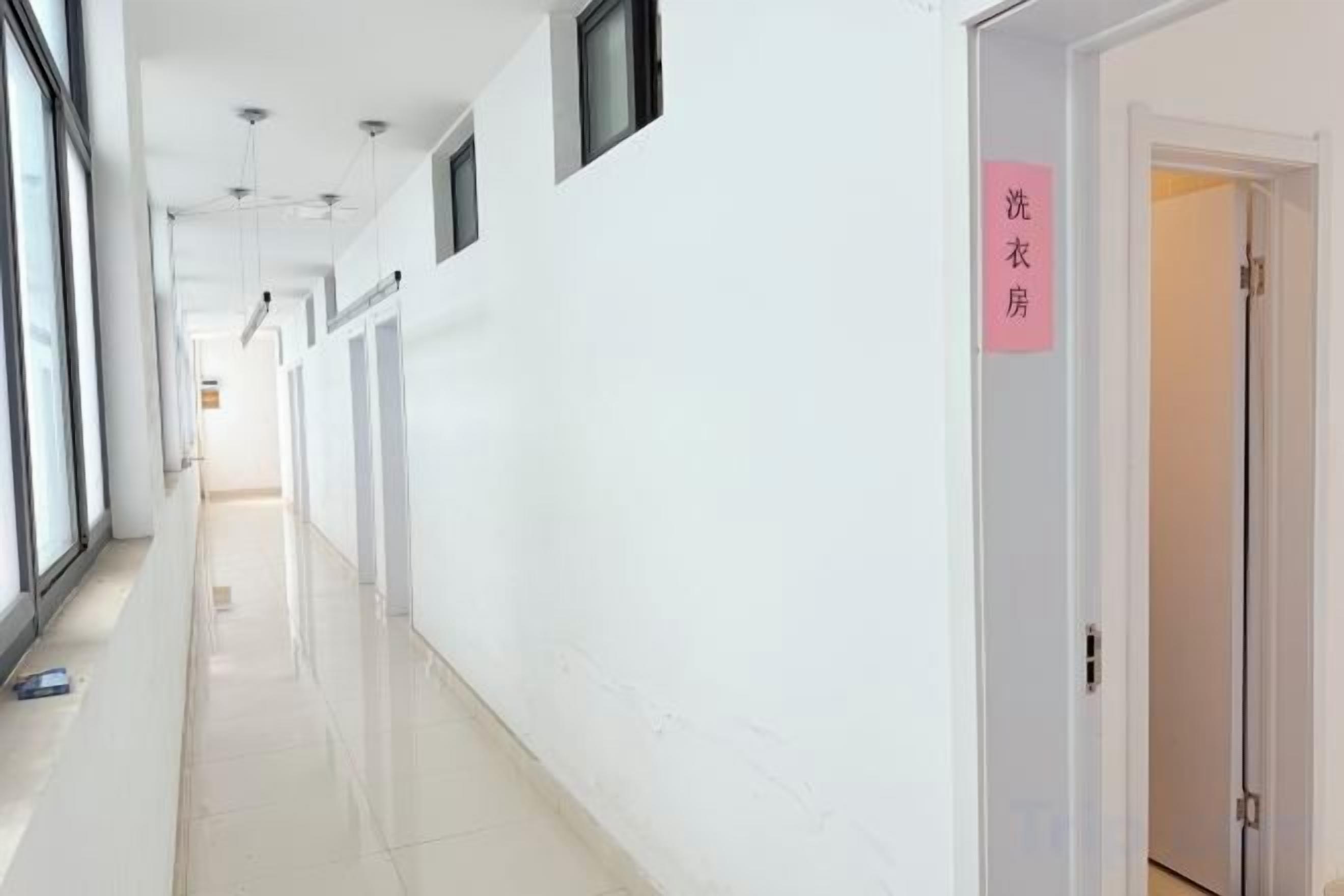 A hallway with a sign indicating a laundry room, a door, and a window on the left.