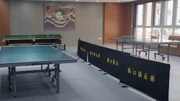 Una habitación con mesa de ping pong, mesa de billar y zona de estar con vistas al exterior.