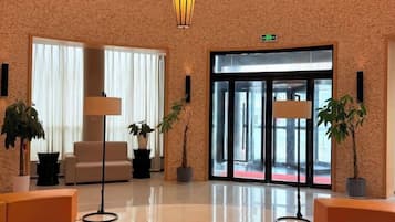 A lobby with a reception desk, seating area, and a large glass door entrance.