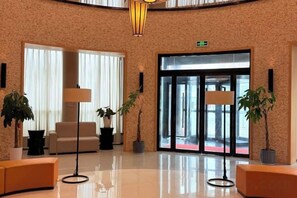 A lobby with a reception desk, seating area, and a large glass door entrance.
