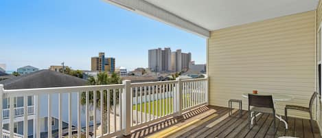 A wooden deck with a white railing, a table, and two chairs.