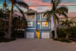 A two-story house with a front entrance, garage doors, and a driveway. - Pier to Pier Paradise by Beach Boutique Rentals (Anna Maria)