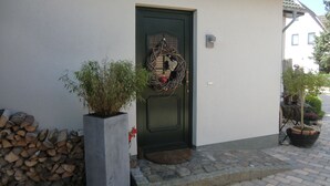 A house with a green door, a potted plant, and a stack of firewood. - Quietly located vacation apartment with garden (Born a. Darß)