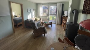 A living room with a sofa, armchairs, a coffee table, a TV, and a fireplace. - Quietly located vacation apartment with garden (Born a. Darß)
