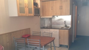 A compact kitchen with wooden cabinets, a microwave, a dishwasher, and a sink.
