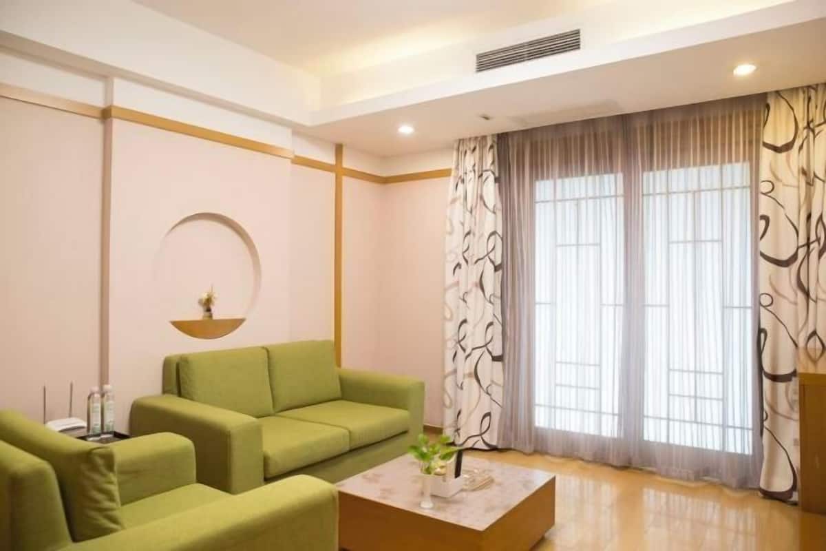 Ein modernes Wohnzimmer mit einem grünen Sofa, einem Couchtisch und einem großen Fenster mit Vorhängen.