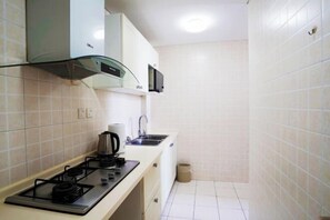 Una cocina pequeña equipada con estufa a gas, microondas y pileta.