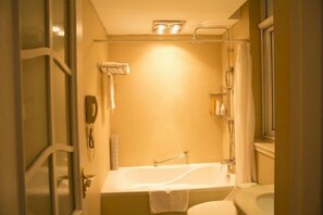 Baño con bañera, inodoro y cabina de ducha de vidrio.