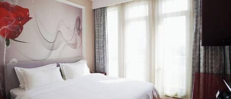 Un dormitorio con cama, un ventanal con cortinas y una pared con diseño floral.