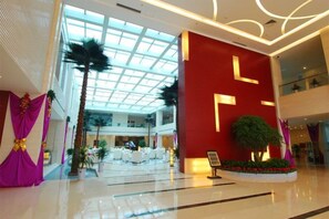 Un amplio atrium con techo alto, un área de estar central y una pared decorativa roja.