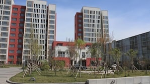 A modern building with multiple floors, a landscaped area with trees, and a clear sky. - Keyuan Business Hotel (Jining)