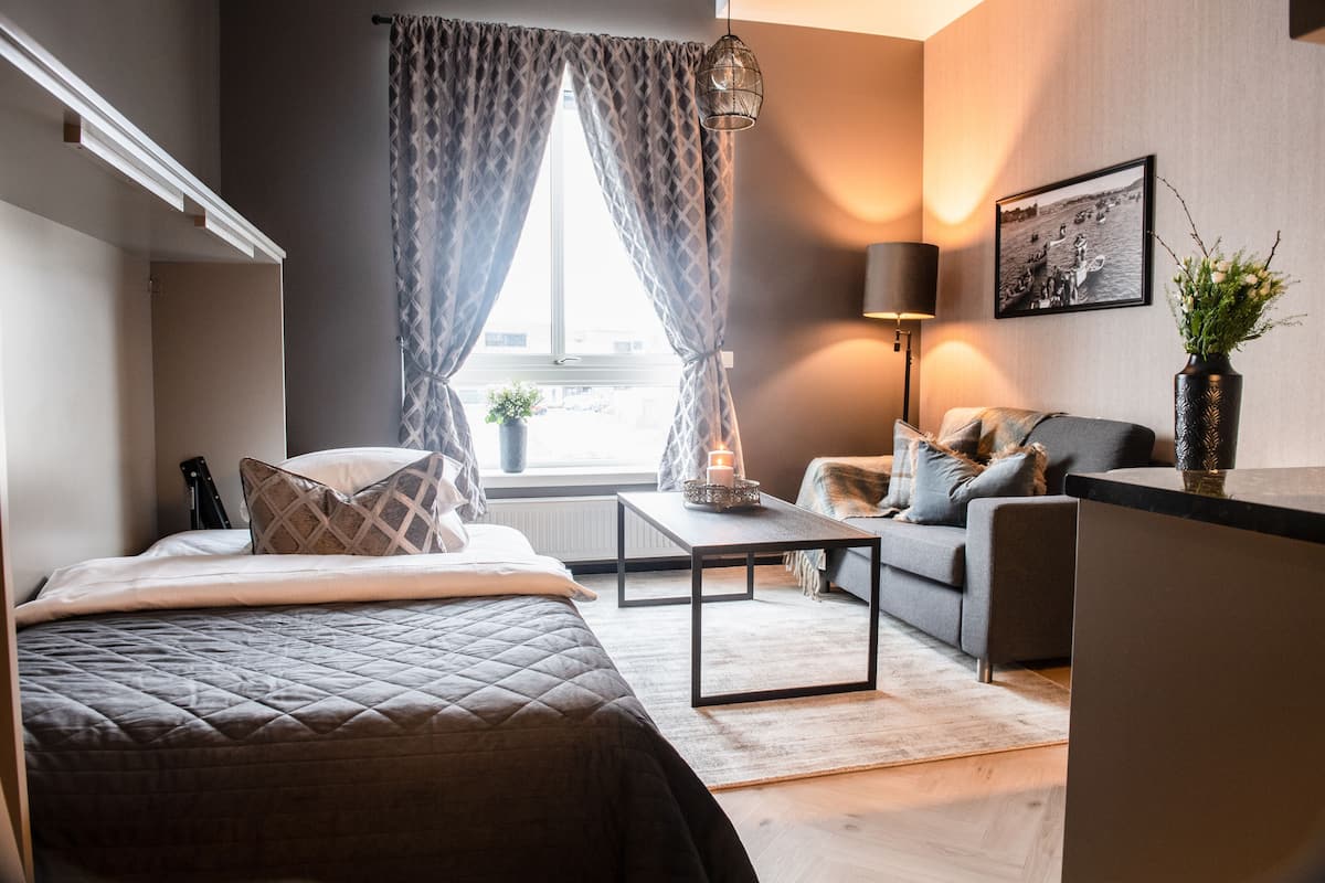 Une chambre à coucher moderne avec un lit, un canapé, une petite table et une lampe.