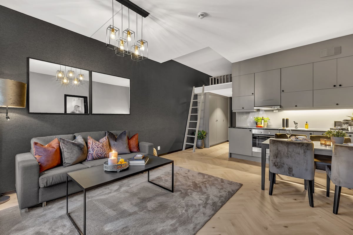 Un salon moderne avec un canapé gris, une table basse et un coin repas comprenant une table et des chaises.