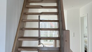 A wooden staircase with a modern design, leading to a bright room with a large window. - Spacious vacation home near the beach in a quiet location in Rosenhagen (Dassow)
