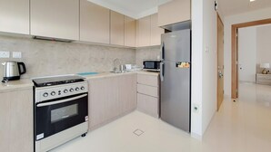 A modern kitchen with a built-in oven, microwave, and refrigerator. - GreenFuture - Panoramic City View From This High-Rise Chic Condo (Dubai)