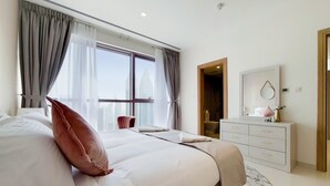 A hotel room with a large bed, a bedside table, a dresser, and a window with curtains. - GreenFuture - Panoramic City View From This High-Rise Chic Condo (Dubai)