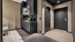 Habitación de hotel moderna con kitchenette, un sofá y una puerta que da a otra habitación.