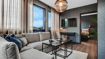 A modern living room with a sofa, coffee table, and a TV mounted on the wall.