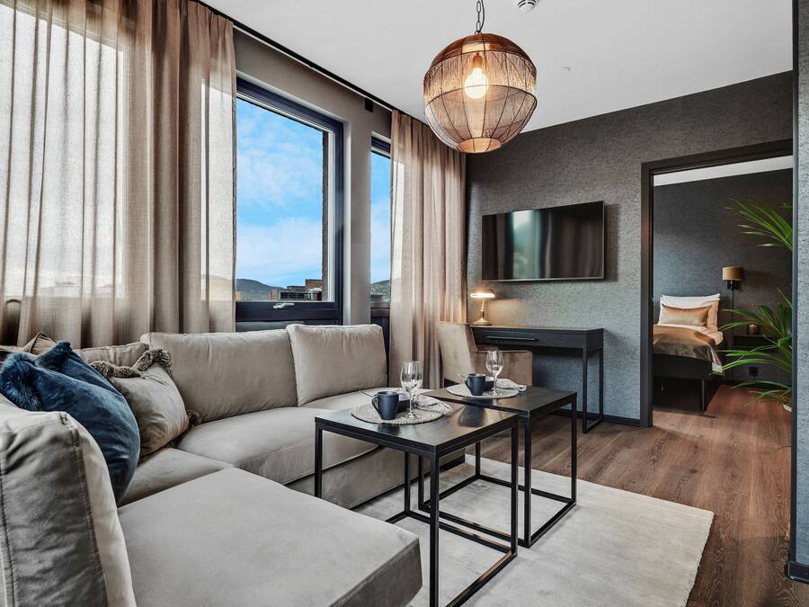 A modern living room with a sofa, coffee table, and a TV mounted on the wall.