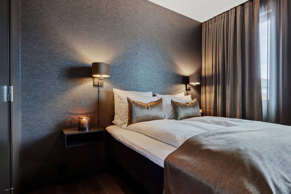 Habitació d'hotel moderna amb un llit gran, dues làmpades de nit i una tauleta de nit.