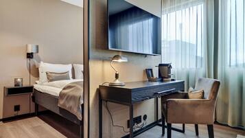 Une chambre d’hôtel moderne équipée d’un lit, d’un bureau, d’une chaise, d’une télévision, d’une lampe et d’une table de chevet.