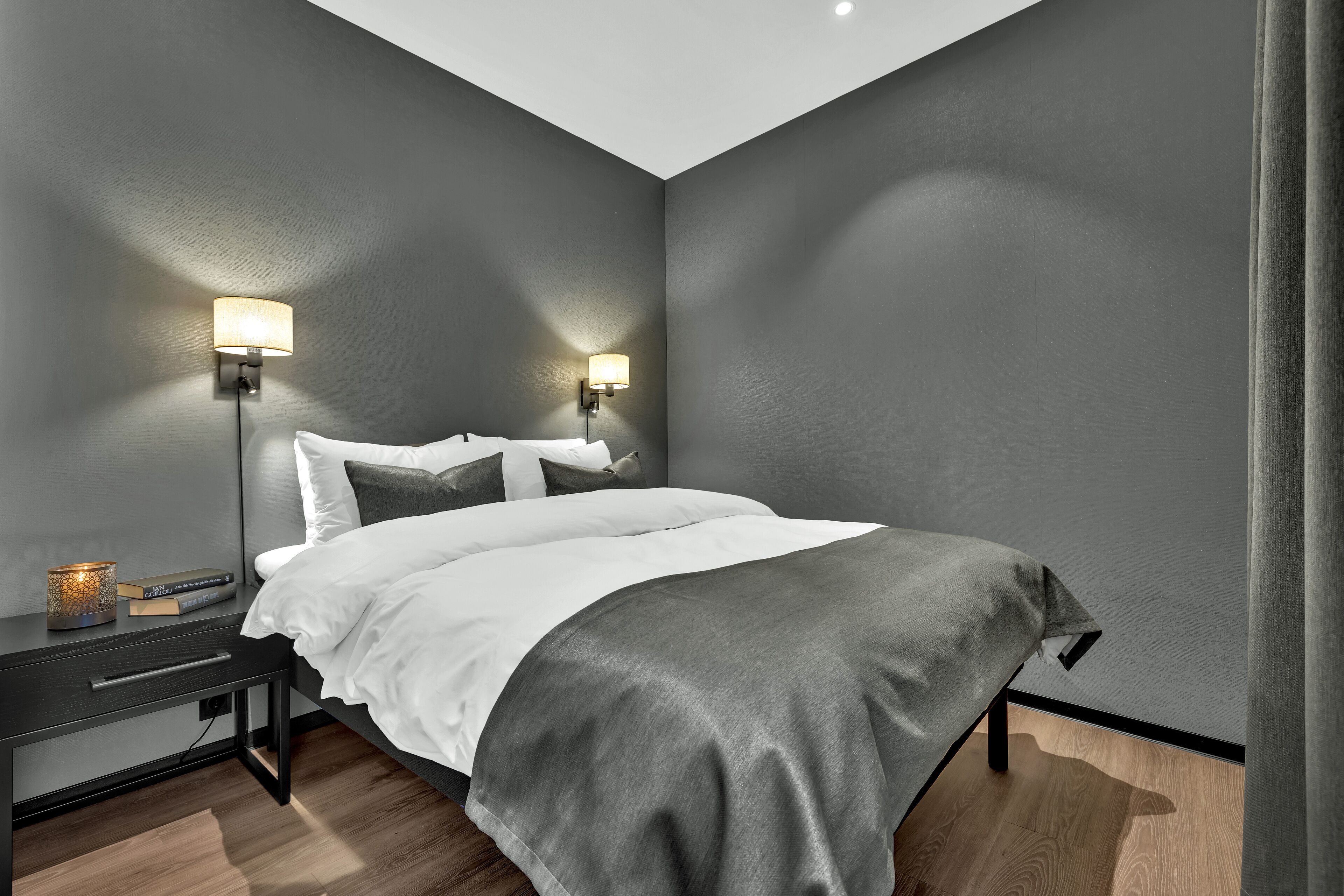 Un dormitorio moderno con una cama, dos lámparas de noche, una mesita de noche y una mesa de noche con lámpara.
